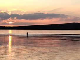 A person standing in water during sunset at Ty Mor in Newport, Pembrokeshire