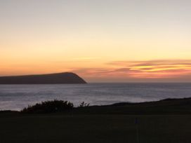 A sunset over the ocean with hills in the background at Ty Mor in Newport, Pembrokeshire