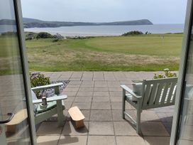 A patio area with chairs and a table overlooking the sea at Ty Mor in Newport, Pembrokeshire