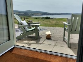 A patio with chairs and a view of the sea and hills at Ty Mor in Newport, Pembrokeshire