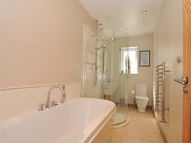 A bathroom with a bath tub, shower, toilet, and sink at Porthmeor in Wadebridge