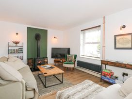 A living room with a television, sofa, and wood burner at Joy's Cottage in Snettisham