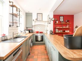 A kitchen with sink and shelves at Joy's Cottage in Snettisham