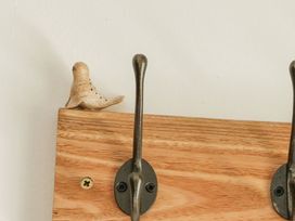 A wooden board with metal hooks and a decorative bird at Joy's Cottage in Snettisham
