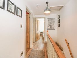 A hallway with framed pictures and doors at Joy's Cottage in Snettisham