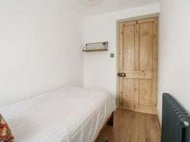 A bedroom with a single bed and a wooden door at Joy's Cottage in Snettisham