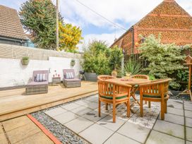 A garden with a table and chairs and lounge chairs at Joy's Cottage Snettisham