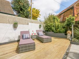 A garden with lounge chairs and potted plants at Joy's Cottage in Snettisham