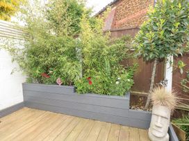 A garden with potted plants and wooden decking at Joy's Cottage in Snettisham