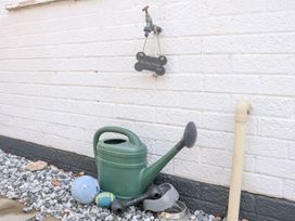 A watering can and dog supplies in an outdoor area at Joy's Cottage in Snettisham