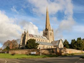 A church building with a steeple and surrounding trees at Joy's Cottage in Snettisham