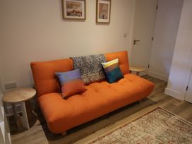 A living room with an orange sofa and side tables at 11 Fountain Court in Falmouth