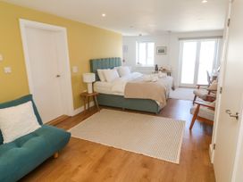 A bedroom with a bed, sofa and chairs at 11 Fountain Court in Falmouth