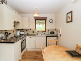A kitchen with an oven, sink, and table at Orchard Cottage in Ledbury