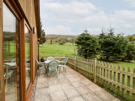 A patio with a table and chairs overlooking a grassy area at Orchard Cottage in Ledbury