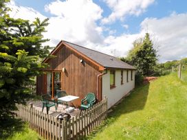 A cottage with a deck and chairs at Orchard Cottage in Ledbury