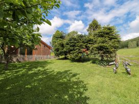 A garden with trees and a wooden building at Orchard Cottage in Ledbury