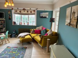 A living room with a yellow sofa and decorative items at Somerby in St. Bees
