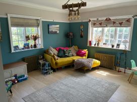 A living room with a yellow sofa and decorative items at Somerby in St. Bees
