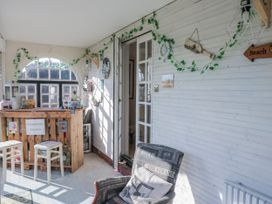 A conservatory with a wooden bar, chairs, and decorative items at Somerby in St Bees