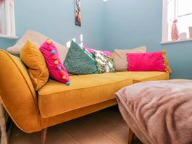 A living room with a yellow sofa and cushions at Somerby in St Bees