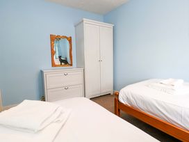 A bedroom with two beds, a dresser, and a wardrobe at Still Waters, Weymouth