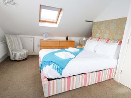 A bedroom with a bed and an armchair at Still Waters in Weymouth