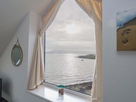 A view of the sea through a window with a curtain at Still Waters in Weymouth