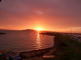 A sunset over the ocean with a road and vehicles at Still Waters in Weymouth