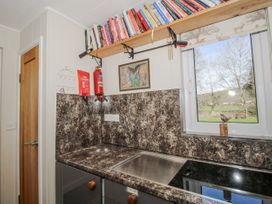 A kitchen with a sink and shelf containing books at Hazel Lodge in Clunton near Clun