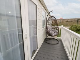 A balcony with a hanging chair at 11, Beachfields