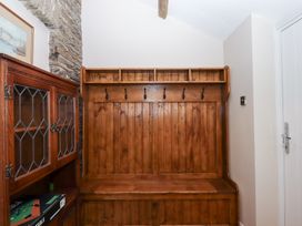 A hallway with a wooden bench and coat hooks at Garden Cottage at the Bowden Estate Stoke Fleming