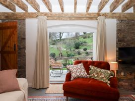 A living room with a red sofa and a door leading outside at Garden Cottage at the Bowden Estate Stoke Fleming