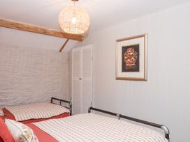 A bedroom with beds, closet, and wall art at Garden Cottage at the Bowden Estate, Stoke Fleming