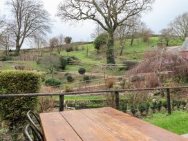 A garden with a wooden table and trees at Garden Cottage at the Bowden Estate Stoke Fleming