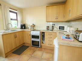 A kitchen with cabinets, oven, sink and appliances at Getws in Ty Croes