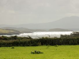 An ocean view with waves and hills at Getws in Ty Croes