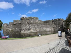 A castle surrounded by water with a pathway and benches at 15 Rose Hill Beaumaris