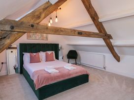 A bedroom with a green bed and chair at Lon Popty in Dolgellau