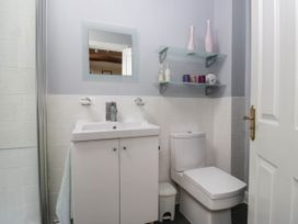 A bathroom with a sink, toilet, and shelf at The Spinney near Milnthorpe