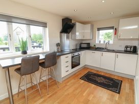 A kitchen with bar stools and appliances at James Ville Marina Lodge 7 in Brigg