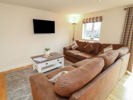A living room with a sofa, coffee table, and television at James Ville Marina Lodge 8 in Brigg