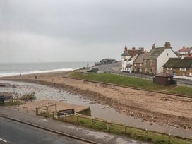 A beach with a view of houses and a road at South Villa Sandsend near Whitby
