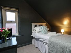 A bedroom with a single bed and flowers on a bedside table at South Villa in Sandsend near Whitby