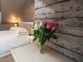 A bedroom with a vase of roses on a nightstand at South Villa in Sandsend near Whitby
