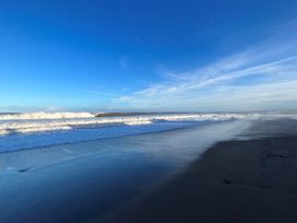 A beach with ocean waves and blue sky at South Villa Sandsend near Whitby
