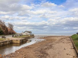 A beach with a building and river at South Villa in Sandsend near Whitby