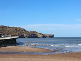 A beach with a cliff and a pier at South Villa in Sandsend near Whitby