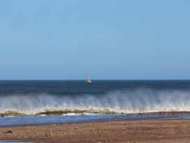 A beach view with waves and a boat at South Villa Sandsend near Whitby