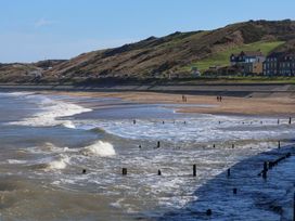 A beach with waves and houses along the shoreline at South Villa Sandsend near Whitby